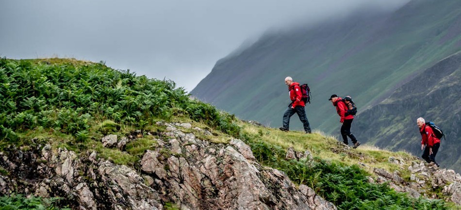 Three mountain rescue individuals climbing up a mountain
