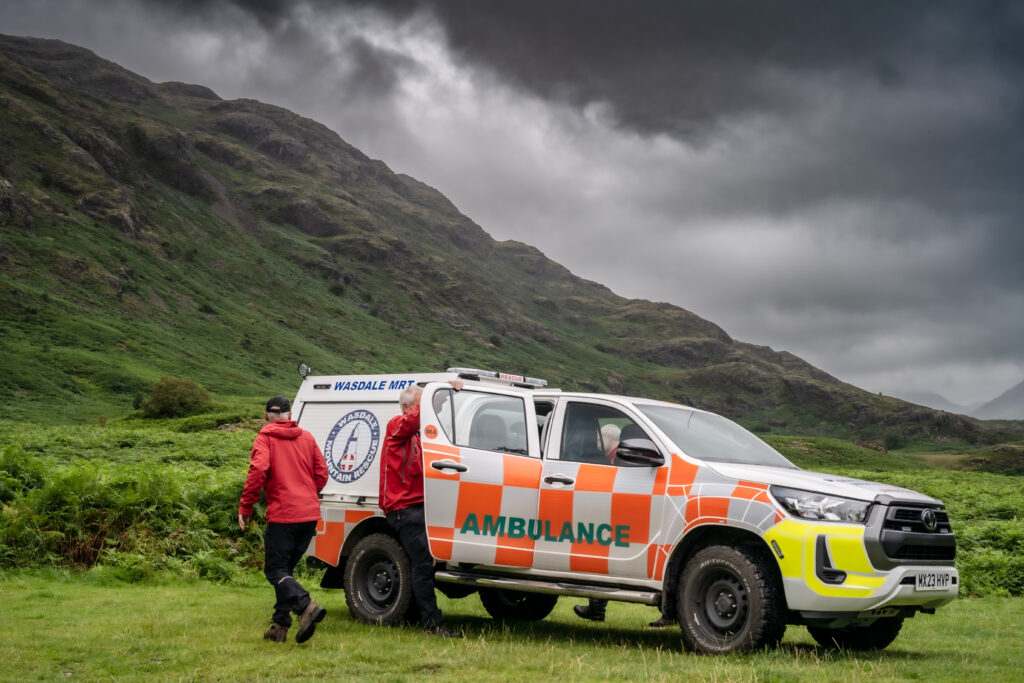 Mountain Rescue Ambulance on a green hillside with 3 male persons