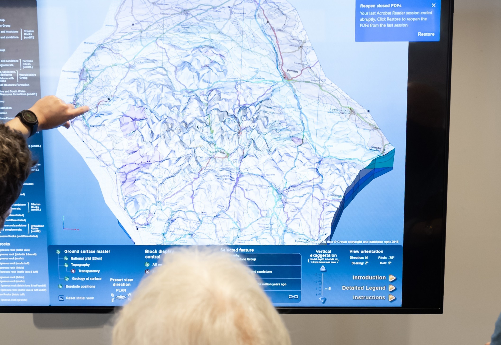 Image shows a tv screen displaying geological map data for an area. Technical drawing diagram on the screen.