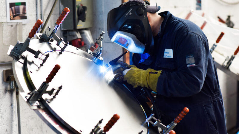 Person working on a waste container wearing a welding mask