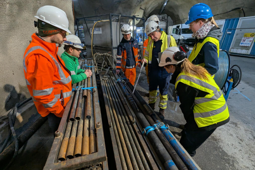 Men and women in high vis and hard hats examining rock core in the an underground research laboratory